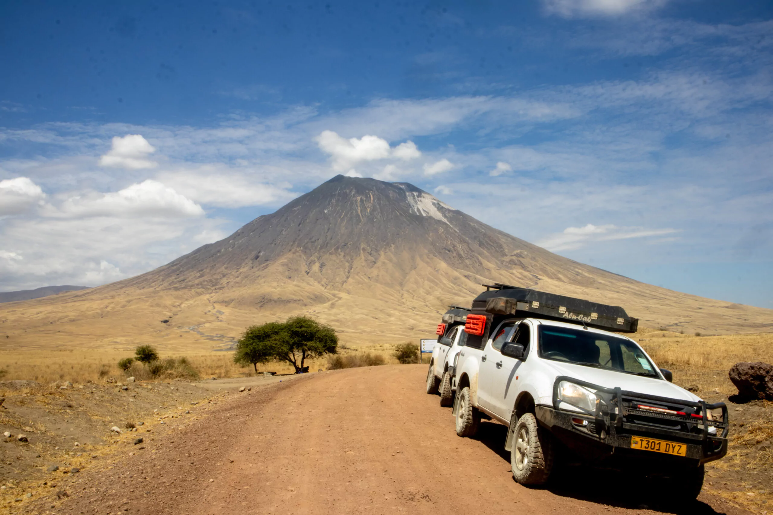 Tansania Camping Safari mit dem Mietwagen Lake Natron Fahrzeuge vor dem Vulkan Ol Doinyo Lengai